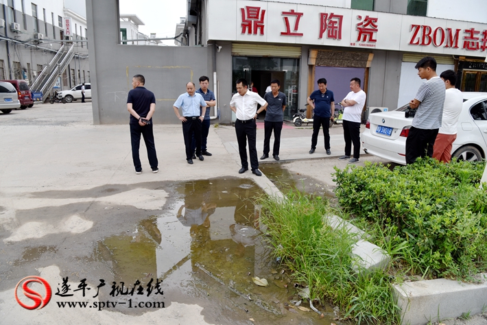 上圖:縣委副書記尹永彪與相關部門負責人在城南建材市場南門外查看積水問題,當即責成市場發展局限時解決。