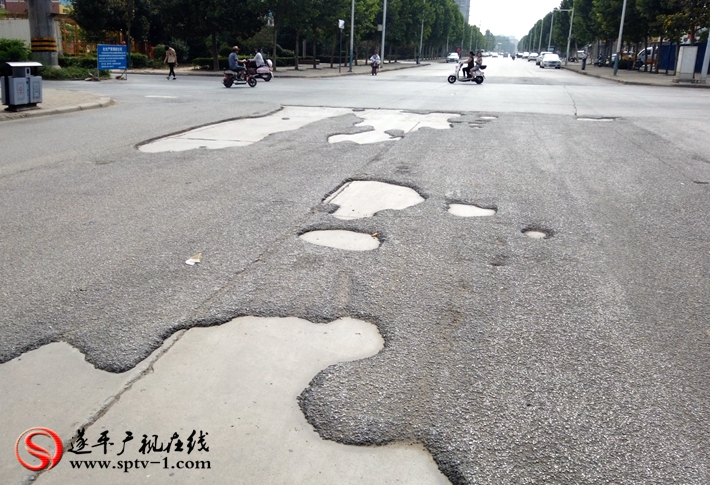上圖:遂周路與金山路交叉口柏油路面破損嚴(yán)重,坑洼不平。